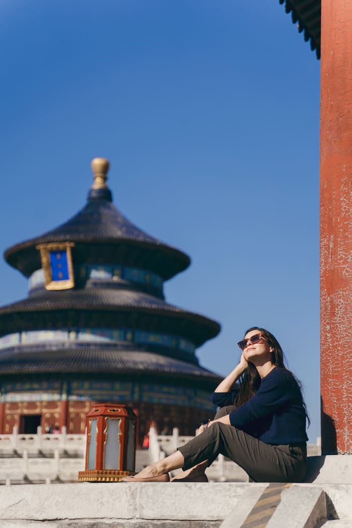 mujer sentada contemplando la vista de fondo un templo chino en beijin