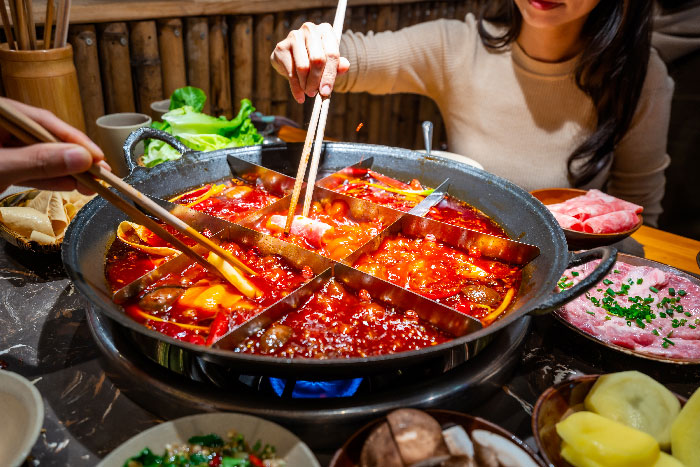 Platillo de comida tipica en chongqing, china, dos personas comiendo del darte con palillos