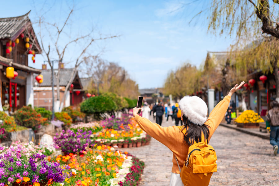 turista vestida con sueter amarillo y gorra disfrutando del paisaje en yunnan china